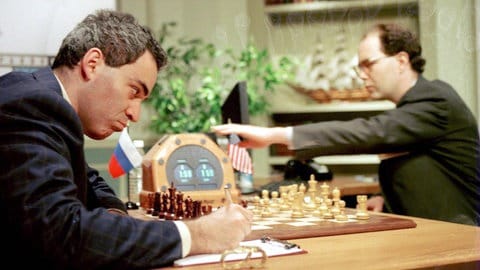 Garri Kasparow aus Russland macht sich am 11. Mai 1997 Notizen. Rechts im Bild Joseph Hoane, der die Züge für den Computer Deep Blue ausführt 