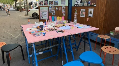 Ein bunter Tisch steht vor dem Container der Kunst-Aktion "Lost & Found" in der Ludwigshafen und lädt mit zahlreichen Stiften und Bastelsachen zum Mitmachen ein