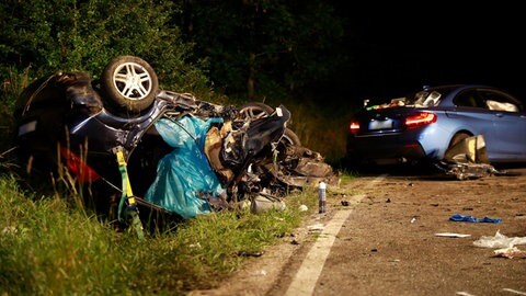 Bild eines Verkehrsunfalls: ein vollkommen zerstörter Wagen liegt auf dem Dach an einer Böschung, auf der Straße steht ein nur teilweise beschädigter größeres Auto. Davor sind Fahrzeugteile und mit Kreide markierte Bremsspuren auf der Straße zu sehen. In unserer Reihe "SWR1 Neuanfang" portraitieren wir Luana: Sie hat einen Raserunfall überlebt, ihr Mann und ihr Baby starben. Trotz des großen Traumas kämpfte sie sich zurück ins Leben.