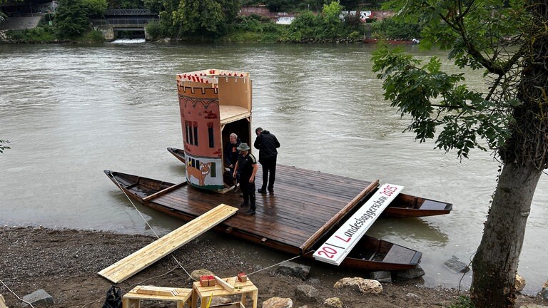 "Landesbaggerschau 2025" steht auf einem Schild, das gerade an ein Themenboot angebracht wird. 