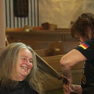 Eine Frau lacht beim Haareschneiden in einer Zweibrücker Kirche