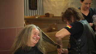Eine Frau lacht beim Haareschneiden in einer Zweibrücker Kirche