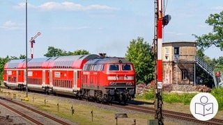 Ein roter Zug der Deutschen Bahn. Der Zug fährt auf Gleisen. Daneben sieht man ein altes Gebäude. Rechts das SWR Logo für Leichte Sprache.
