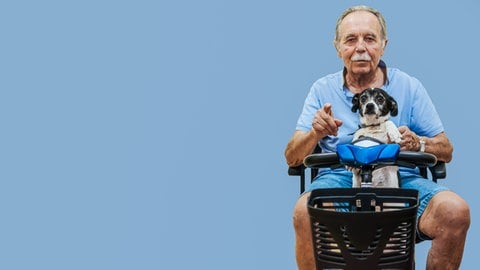 Ein fröhlicher älterer Mann mit seinem Hund auf einem Elektromobil