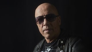 Musiker Toni Krahl blickt vor schwarzen Hintergrund in die Kamera.
