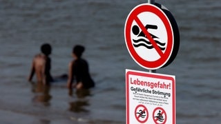 Ein Schild warnt vor gefährlicher Strömung und Lebensgefahr beim Baden im Rhein.