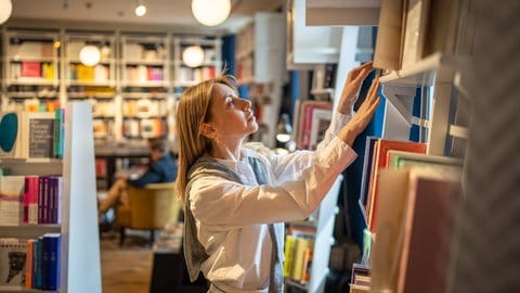 Eine Frau durchsucht ein Bücherregal 