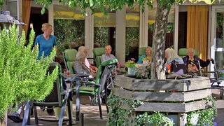 Senioren sitzen auf der Terrasse einer Pflege-WG