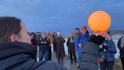 Die Gruppe hört Jutta Gluiber zu bei der Vollmondwanderung mit Wissenswertem über die Kelten im Heidengraben bei Grabenstetten.