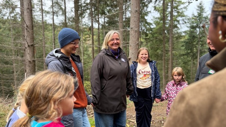 Frau steht mit Kindern im Kreis im Wald