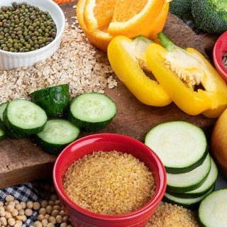 Gesunde Nahrungsmittel wie Gemüse, Vollkornbrot, Hülsenfrüchte, Saaten, Obst auf einem Tisch. Neue Studien zeigen: Unsere Ernährung hat weitreichende Folgen für die Gesundheit – stärker als bislang gedacht. Sie kann chronische Entzündungen, Diabetes oder Herzerkrankungen fördern. Doch eine ausgewogene Ernährung mit Ballaststoffen, Gemüse und Proteinen kann viele Risiken mindern.