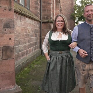 Eine Frau im Dirndl und ein Mann in Tracht lächeln