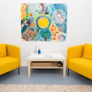 Ein Behandlungszimmer in einer psychotherapeutischen Praxis mit zwei gelben Sesseln.