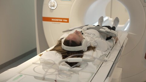 Frau in der Röhre eines Magnetresonanztomographen (MRT). Dieser macht das Körperinnere Schicht für Schicht sichtbar. Die KI analysiert diesen Körperscan auf Fett und Muskelmasse.