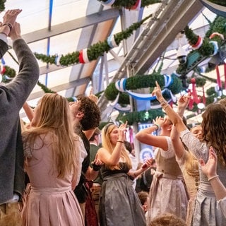 Besucherinnen und Besucher feiern auf einem Volksfest.