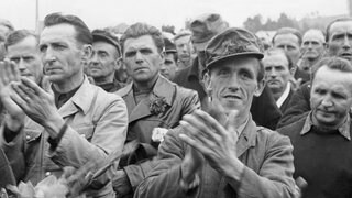 Aus sowjetischer Kriegsgefangenschaft heimgekehrte Männer applaudieren während ihre Begrüßung im Lager Friedland am 9.10.1955. Das kleine Örtchen in Niedersachsen war Schauplatz der "Heimkehr der Zehntausend".