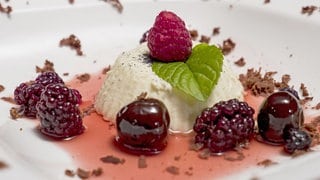Vanille-Creme mit Rumtopf und Schokoladenflocken auf einem Teller