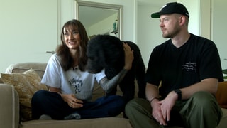 Königspudel Marley sitzt zwischen Lydia und Raffael auf der Couch.