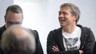 Michael Ballweg (r), Gründer der "Querdenken"-Bewegung, steht mit seinen Anwälten in einem Saal des Landgerichts Stuttgart. 