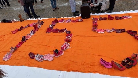 155 Schuhpaare sind so aufgestellt, dass sie die Zahl 155 bilden. Eine Aktion der Bewegung One Billion Rising. Die Schuhe sollen als Mahnung und Gedenken an die 155 Frauen dienen, die im Jahr 2023 in Deutschland von ihrem Partner oder Ex-Partner getötet wurden. 