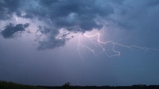 Ein Blitz zuckt bei einem Sommergewitter am abendlichen Himmel (Archivbild).