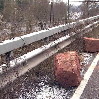 Am Rand einer Landstraße liegen zwei große Felsbrocken