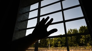 Eine Hand hinter Gittern (Symbolbild)
