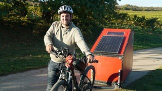 Junger Mann mit Fahrrad und Caping-Anhänger