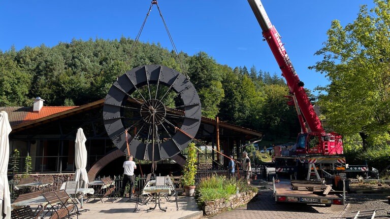 Mit Hilfe von Spanngurten und einem Kran wird das Wasserrad abgesenkt. 