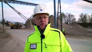Heinz Schlecht ist Betriebsleiter des Kieswerks Meißenheim. Er trägt eine gelbe Schutzjacke und einen weißen Helm.