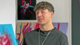 Künstler Fabian Utta vor einigen seiner Bilder