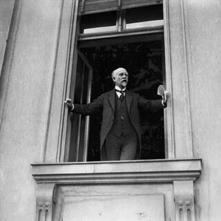 Nachgestelltes Foto: Philipp Scheidemann ruft die Republik aus. Am 9. November 1918 verkündet Reichskanzler Max von Baden die Abdankung des Kaisers. Gleichzeitig übertrug er das Amt des Reichskanzlers an Friedrich Ebert, den Führer der Mehrheits­sozialdemokraten. Am Nachmittag rief Philipp Scheidemann von einem Fenster des Reichstages die Republik aus. Am Abend proklamierte Karl Liebknecht seinerseits von einem Balkon des Schlosses die „Freie Sozialistische Republik Deutschlands“.