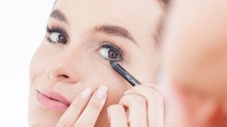 Eine junge Frau benutzt einen Kajalstift am unteren Wimpernkranz. Symbolfoto.