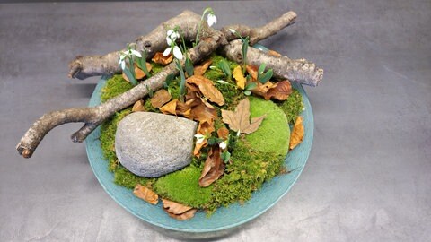 Winterliche Dekoration mit Schneeglöckchen, Moos, Ästen und Zweigen