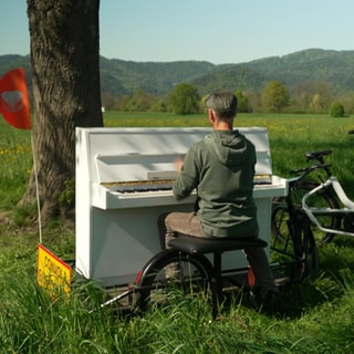 Pianist Christian sitzt an seinem Klavier und spielt in der Natur.