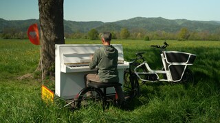 Pianist Christian sitzt an seinem Klavier und spielt in der Natur.
