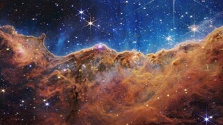 Diese Landschaft aus Bergen und Tälern, die mit glitzernden Sternen übersät ist, ist eigentlich der Rand einer nahe gelegenen, jungen Sternentstehungsregion namens NGC 3324 im Carina-Nebel. Das Bild wurde vom neuen James-Webb-Weltraumteleskop der NASA im Infrarotlicht aufgenommen.