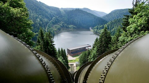 Stahlrohre verlaufen in Richtung eines Pumpspeicherwerks, das an einem Staubecken liegt. 
