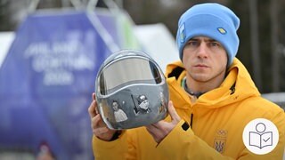 Der ukrainische Sportler Wladyslaw Heraskewytsch. Er hält einen Helm. Auf dem Helm sind Gesicht von getöten Sportlern aus der Ukraine. Rechts das SWR Logo für Leichte Sprache.