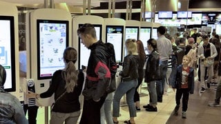 Gäste in einem Schnellrestaurant geben ihre Bestellung über ein Terminal ein