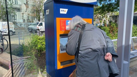 Eine ältere Frau ist dabei, ein Ticket am Automaten für die Fahrt im ÖPNV zu lösen. 