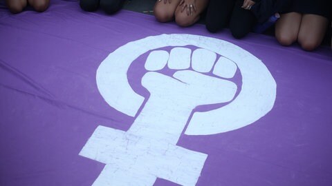 Ein lilafarbenes Transparent mit dem Zeichen des Weltfrauentages: Eine geballte Faust in dem Symbol für weibliches Geschlecht. Viele Frauen demonstrieren am Weltfrauentag gegen Benachteiligung und Unterdrückung.