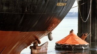 Mitglieder der Umweltschutzorganisation Greenpeace schwimmen am 13.10.1980 in einer roten Rettungsinsel vor dem Bug des Abfalltankers "Kronos", der in Nordenham auf der Weser vor Anker liegt