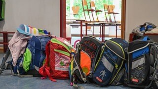 Schulranzen stehen in einer Grundschule vor einem leeren Klassenzimmer (Symbolbild).