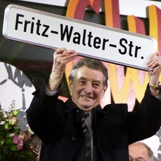 Der 61-fache Nationalspieler, Weltmeister von 1954 und Ehren-Spielführer der deutschen Nationalelf, Fritz Walter (rechts), hält am 31.10.2000 neben dem Kaiserslautener Oberbürgermeister Deubig ein Straßenschild mit seinem Namen hoch