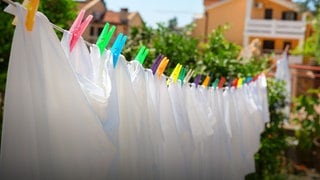weiße Wäsche hängt mit bunten Wäscheklammern an einer Wäscheleine