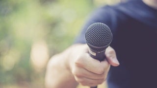 Hand streckt Mikrofon entgegen: Wir stellen die Autorinnen und Autoren von Das Wissen vor