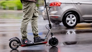 Ein Mann fährt mit einem E-Scooter auf der Straße.