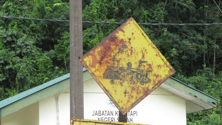 Handgemalt, aber funktionsfähig: Warnschild am unbeschrankten Bahnübergang.