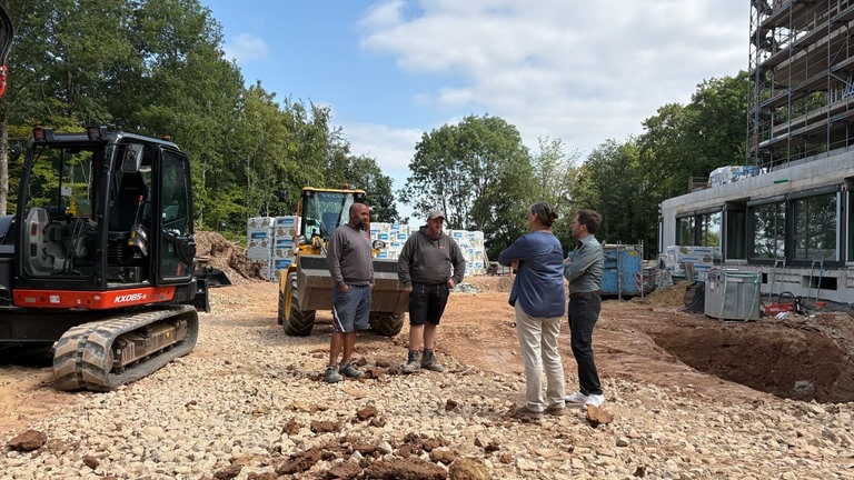 Vier Personen unterhalten sich auf der Baustelle vom Kinderhospiz in Trier. 